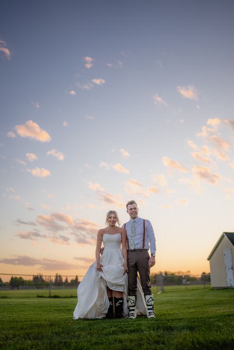 Couple in a field under a pastel sunset sky